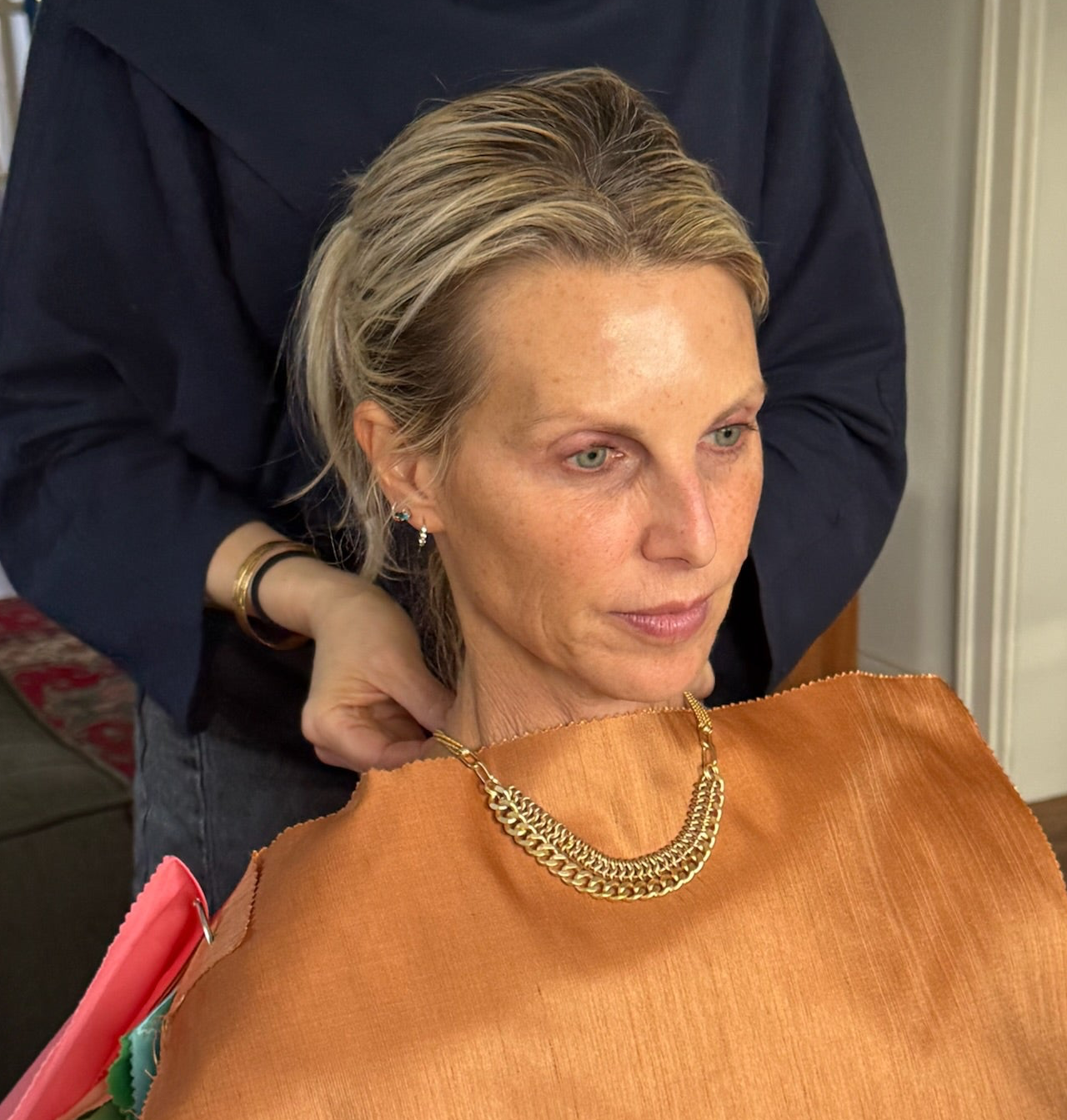 Sara Silvio placing a gold Sara Silvio necklace on a True Spring client during Complete Integration color analysis session showing metal harmony with International Image Institute color drapes