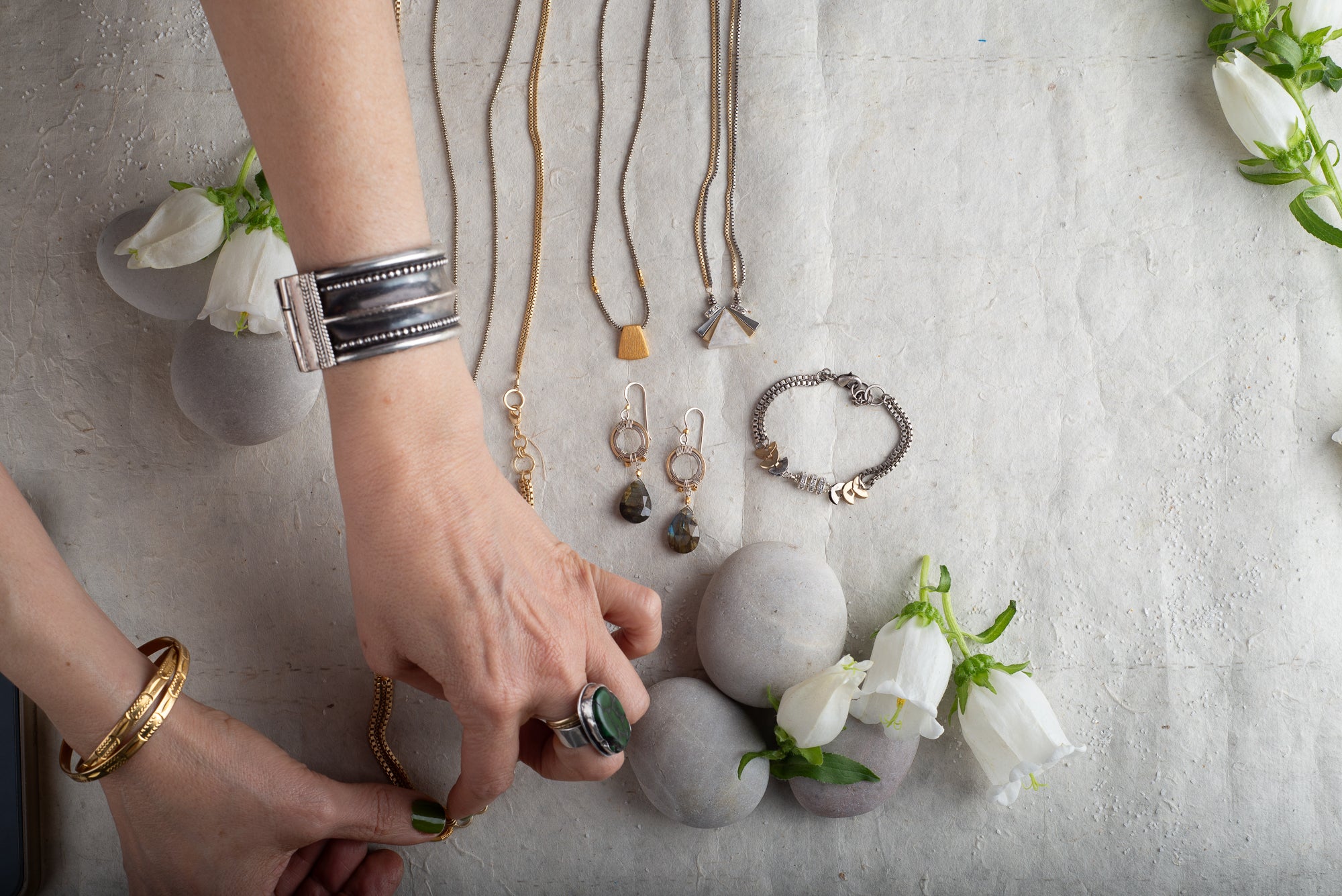 Sara Silvio arranging handcrafted jewelry with stones and metals — seasonal color palette jewelry design and color analysis Rochester NY